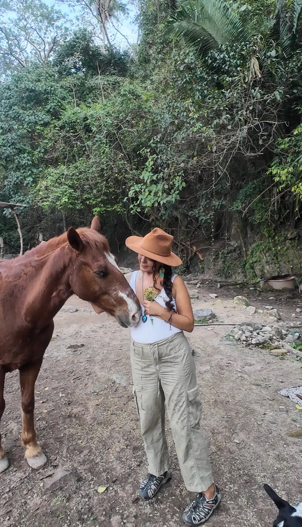 Erika con sombrero y un ramo de flores mientras un caballo alazán se acerca a su pecho