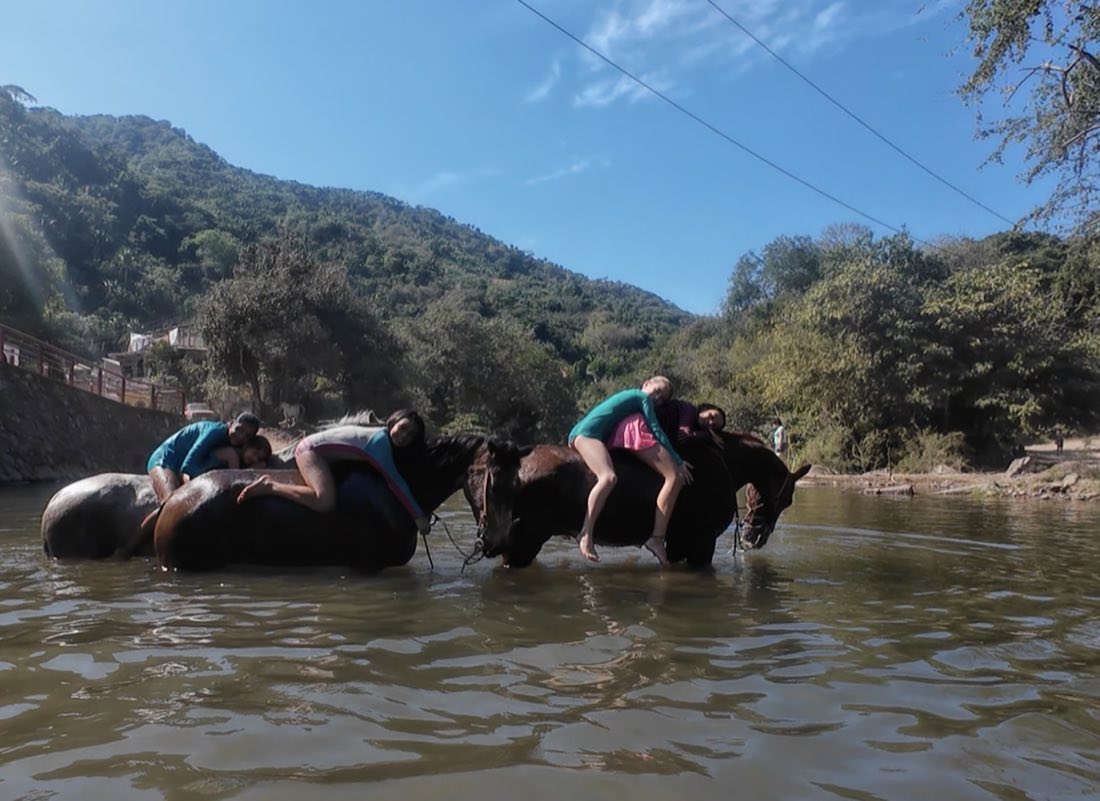 Un grupo cruza el río caminando junto a los caballos